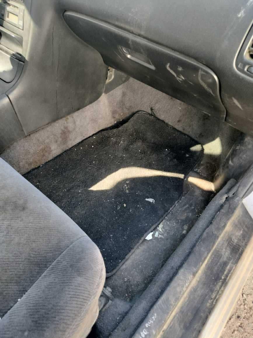 Car interior with a dirty black floor mat and gray seat upholstery.