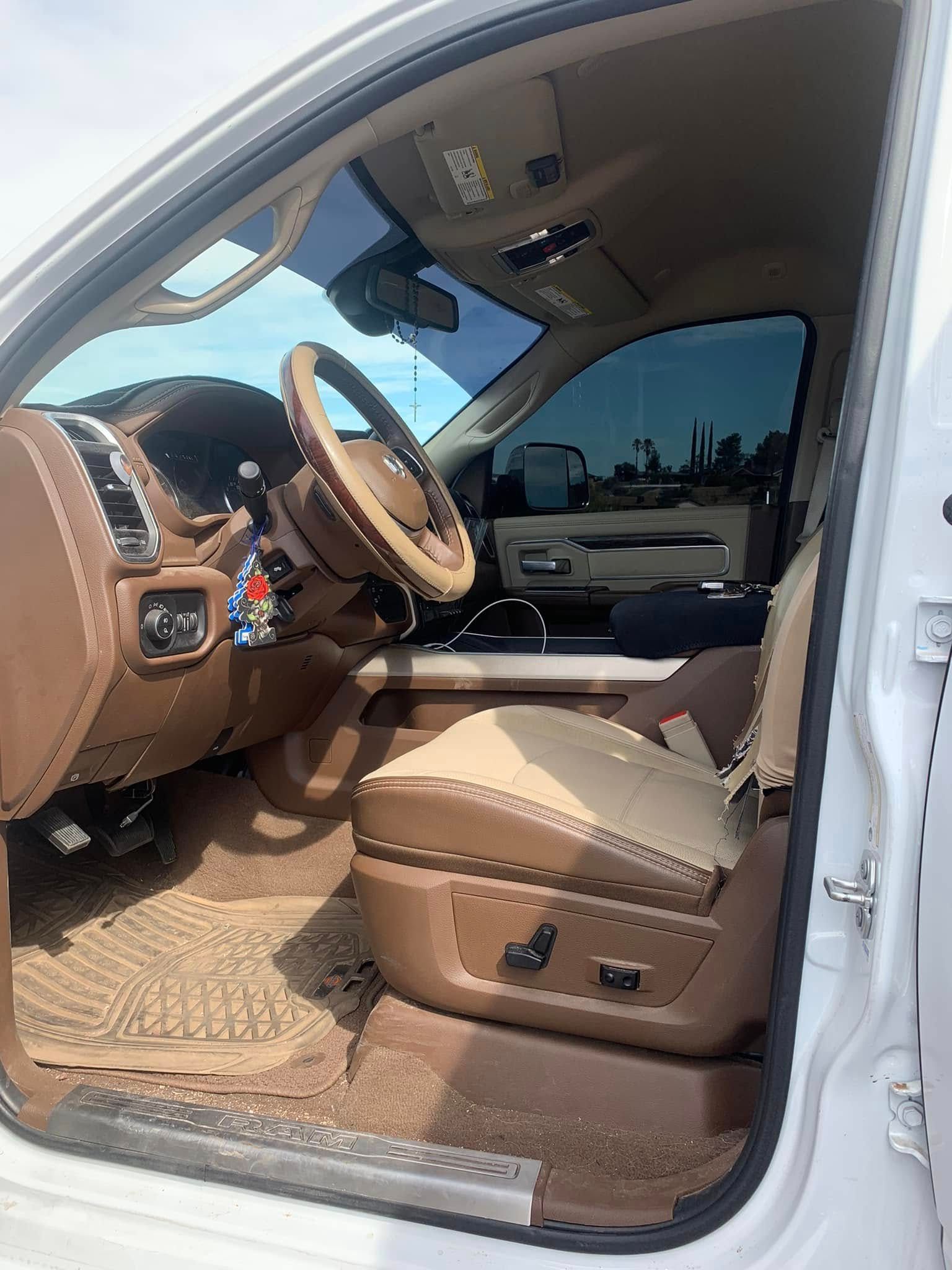 Open car door showing tan leather interior and front seat with dashboard and steering wheel