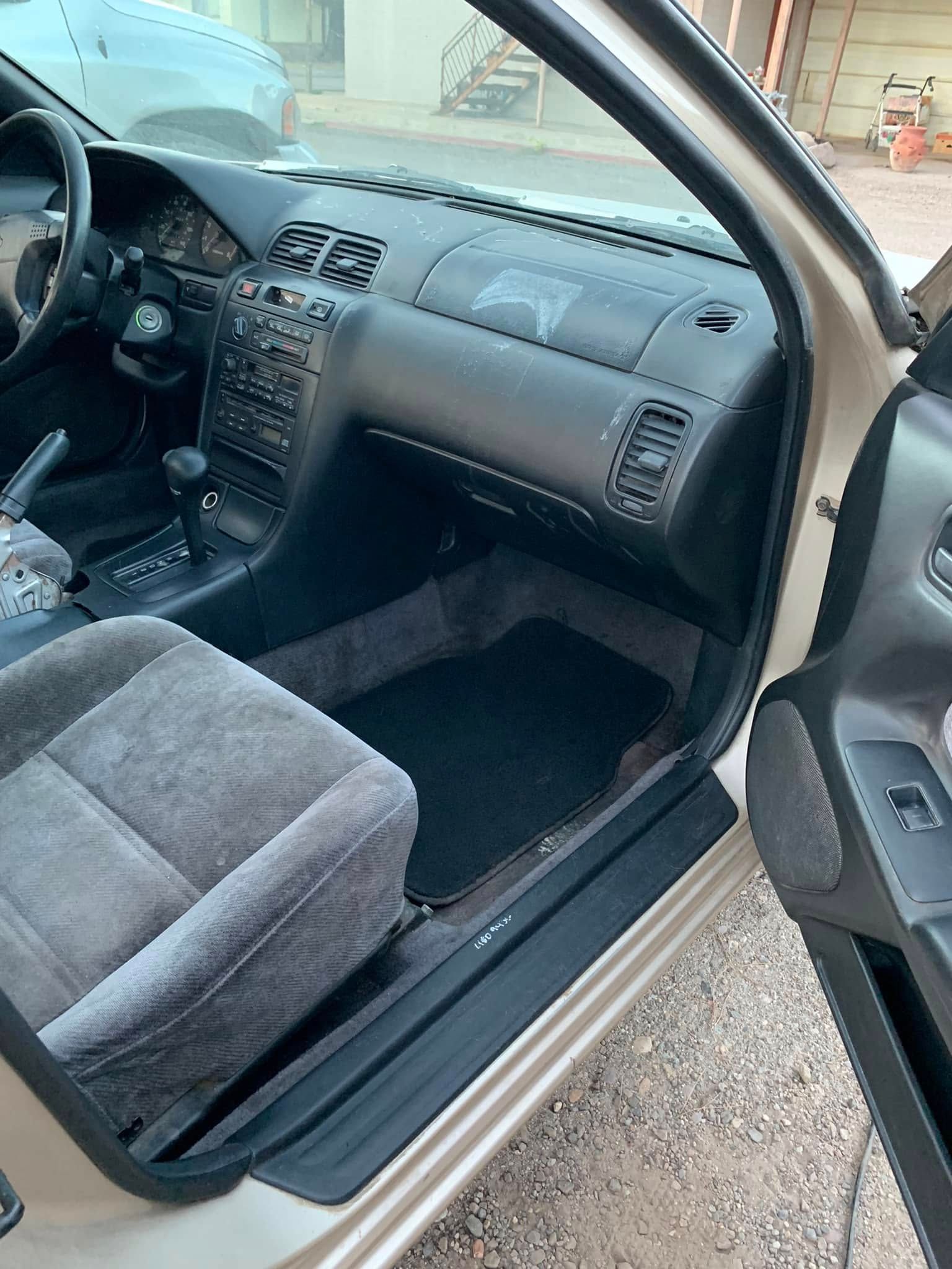 Open car passenger door showing a gray cloth seat, dashboard, and black interior trim