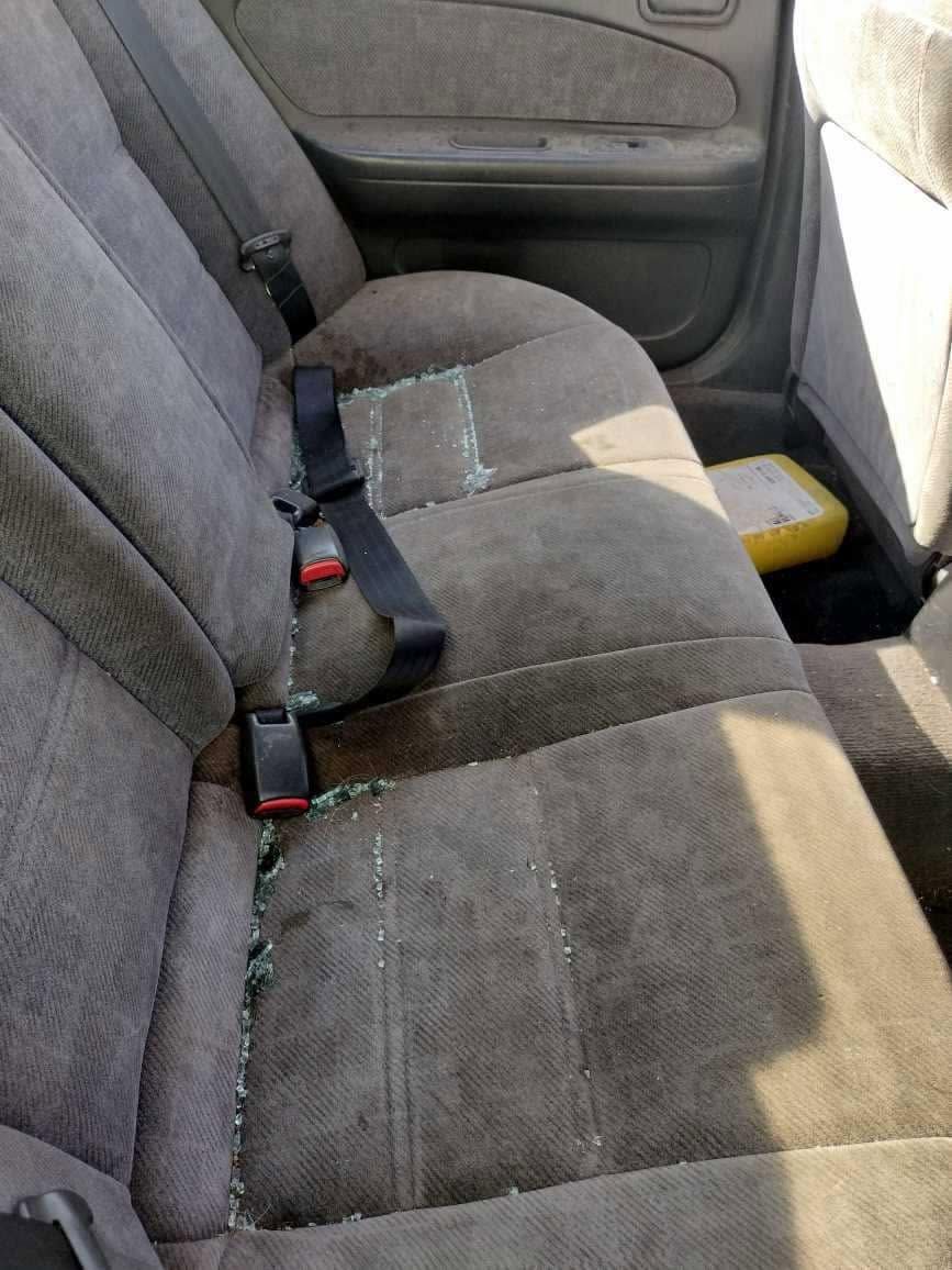 Car back seat with gray upholstery and seat belts, showing a yellow box on the floor.