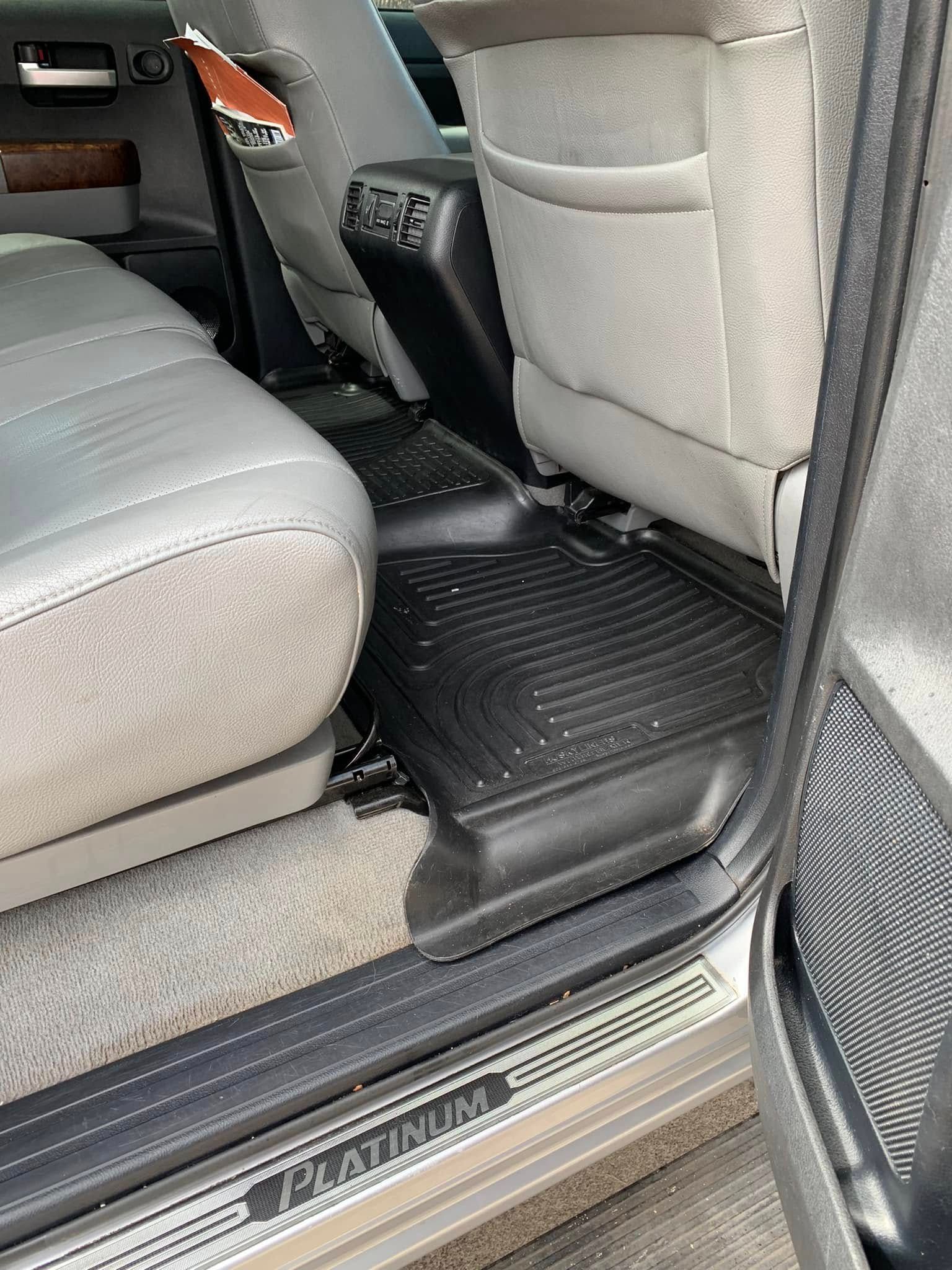 Car interior with a black floor-mounted platform between the back seat and door sill.