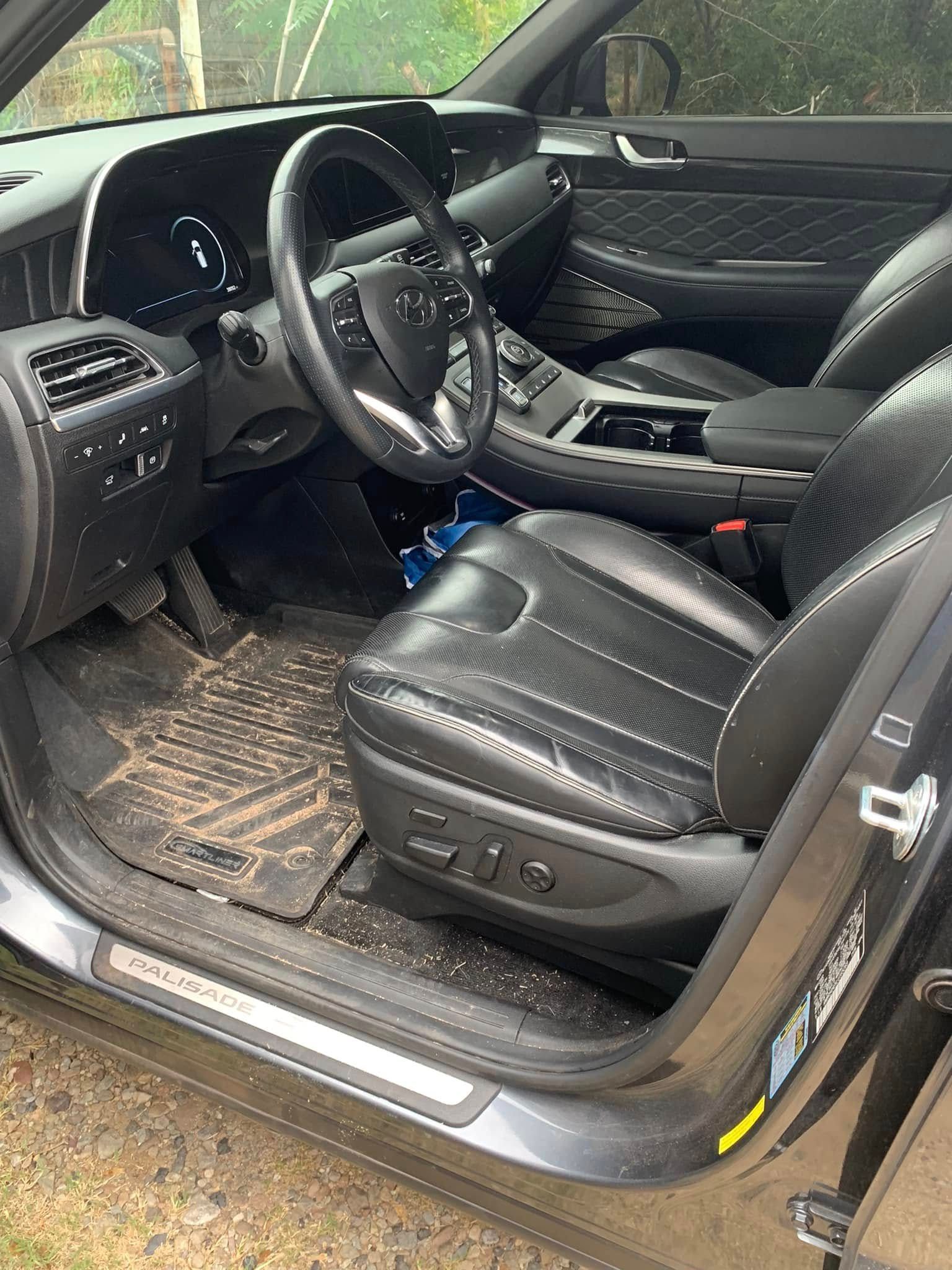 Open car door showing black leather driver’s seat and steering wheel in a modern vehicle interior
