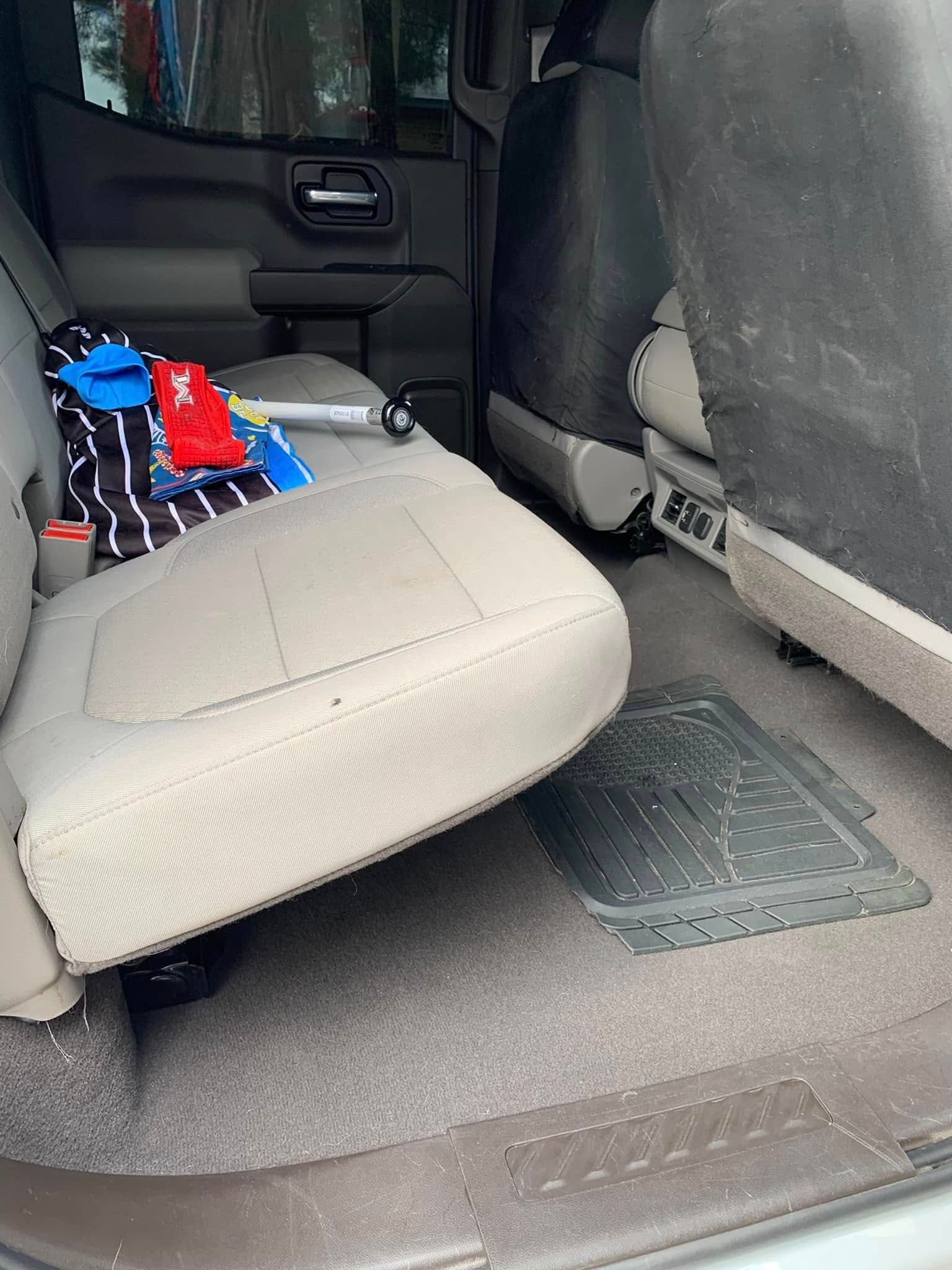 Car interior with folded beige rear seat, black cargo net, and small red and blue items on the seat