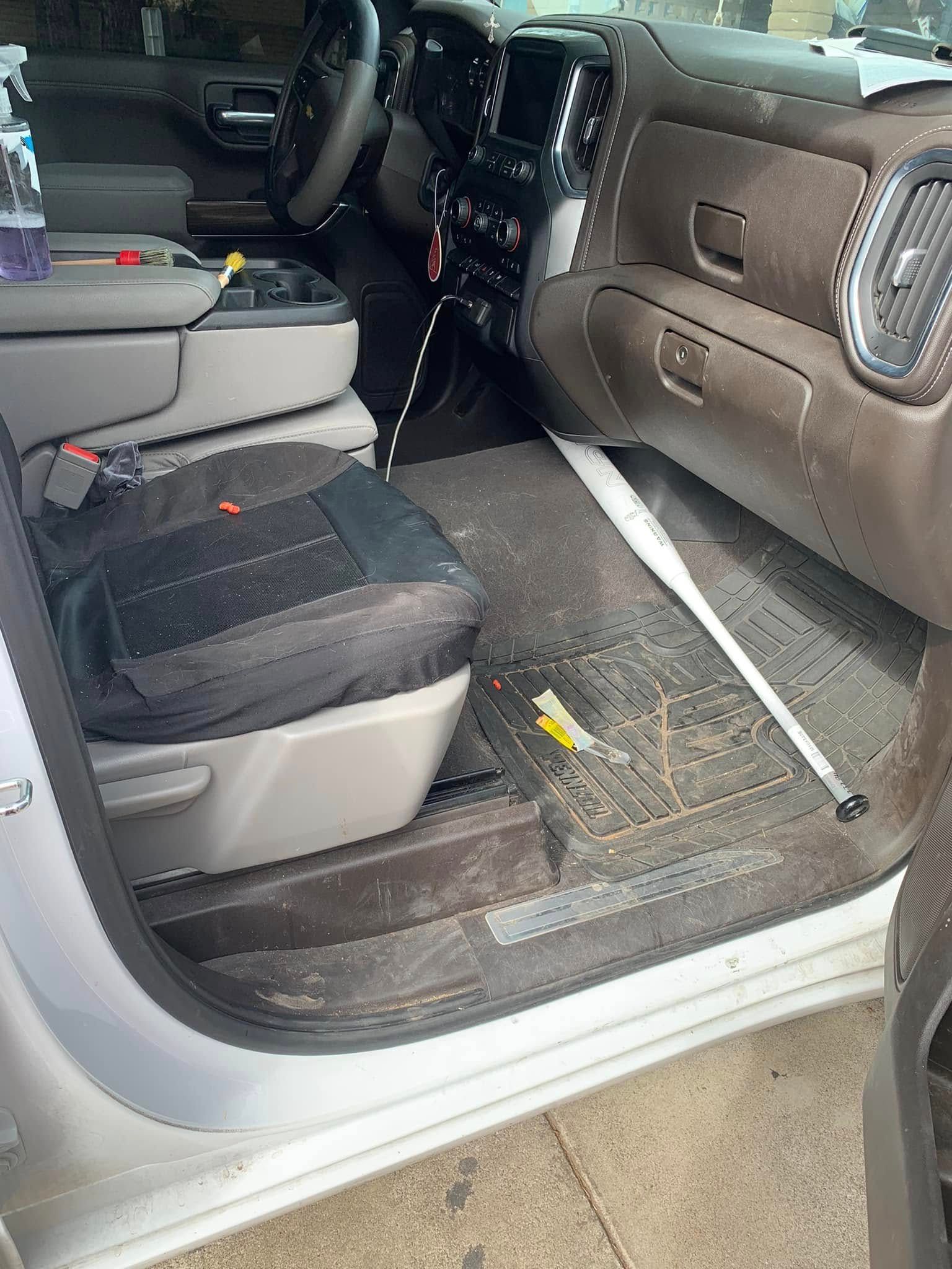 Car interior with open door, black and tan seats, and a folded step board on the floor.