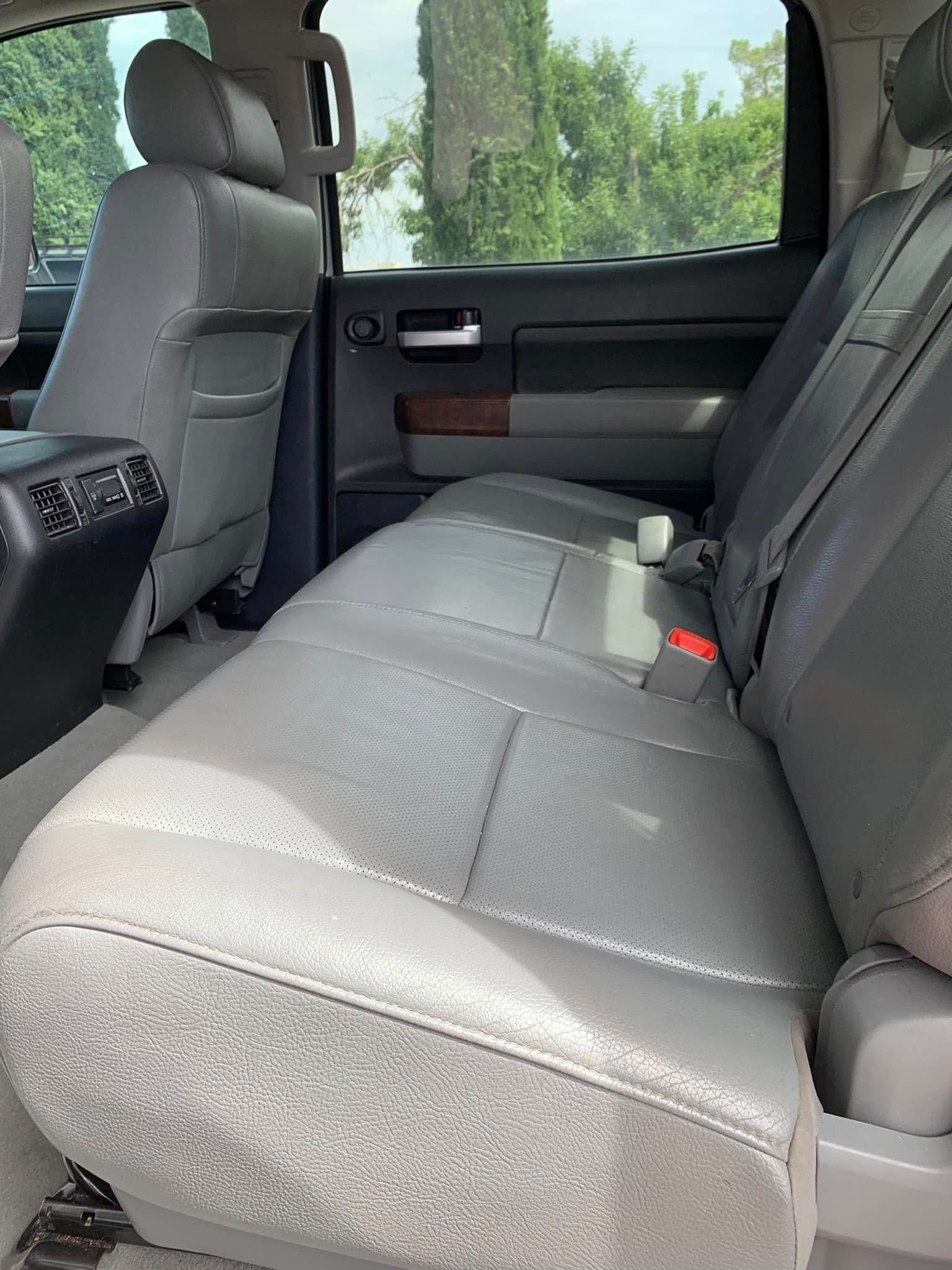 Gray pickup truck back seat with black door panel and sunlit windows, viewed from the side