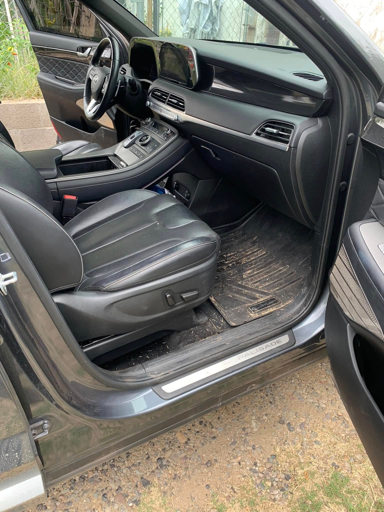 Open car door showing black leather interior and front seat on a muddy driveway