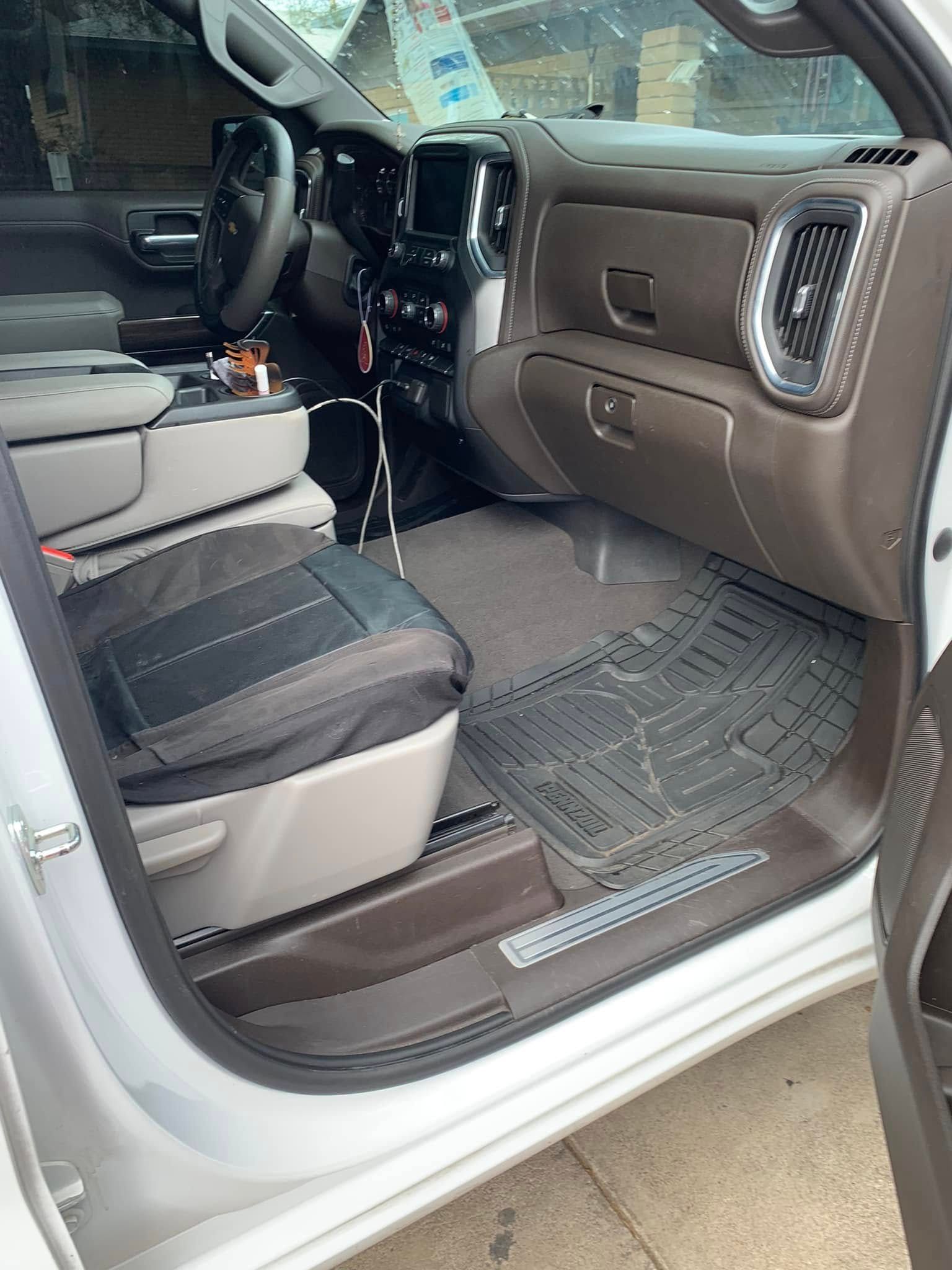 Interior of a white pickup truck with gray seats and floor mats, viewed from the open passenger door