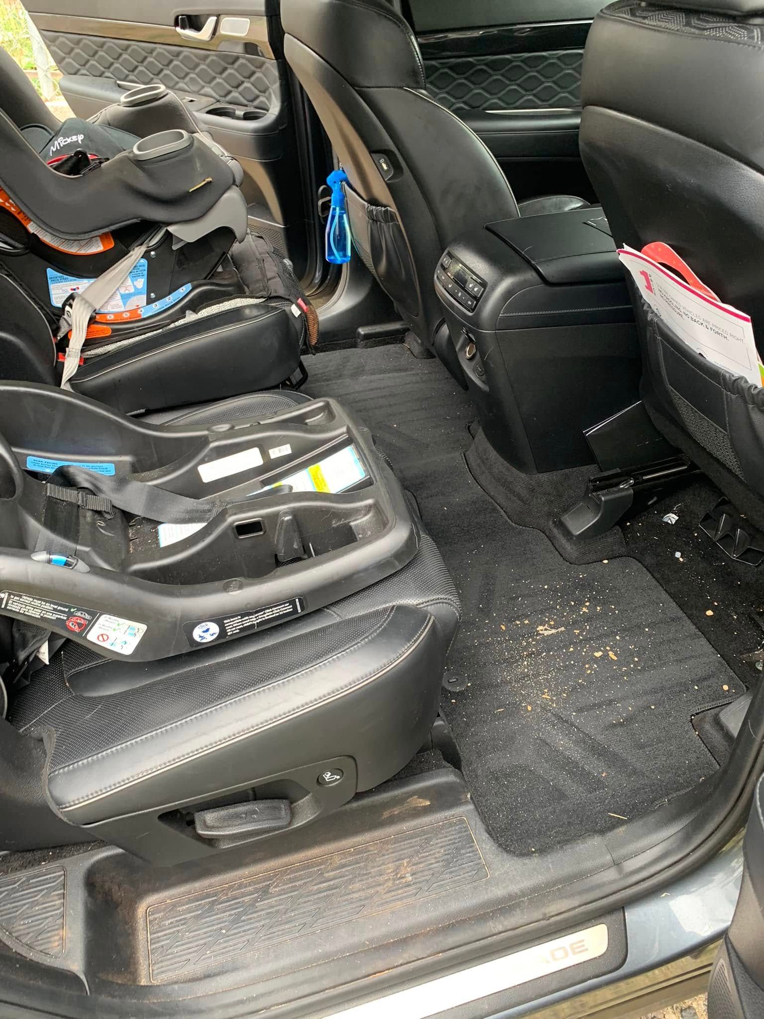 Interior of a minivan with two child car seats and clutter on the floor and seats.