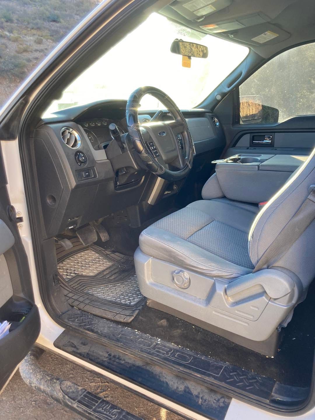 Open driver’s door showing a gray leather truck interior with steering wheel and seat.
