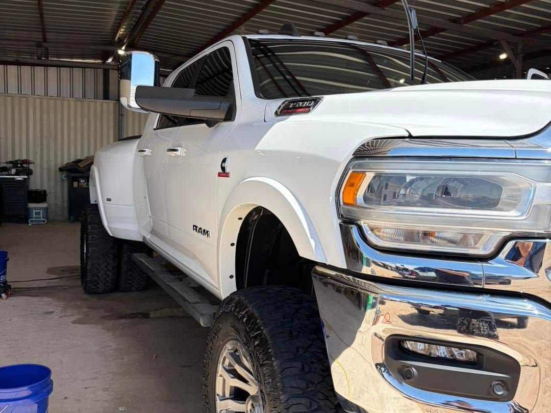 White pickup truck parked in a garage, viewed from the front-left side.