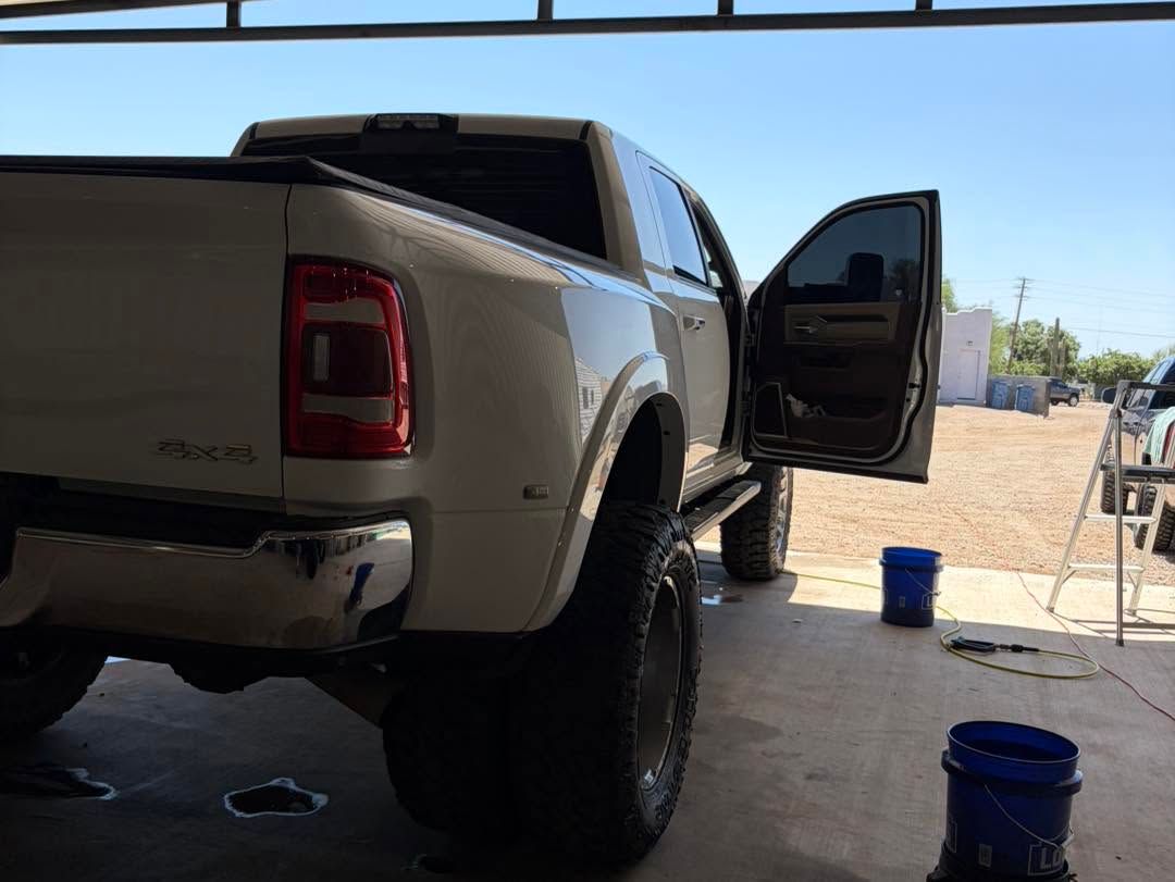 White pickup truck in a garage with the driver door open and blue buckets on the floor.
