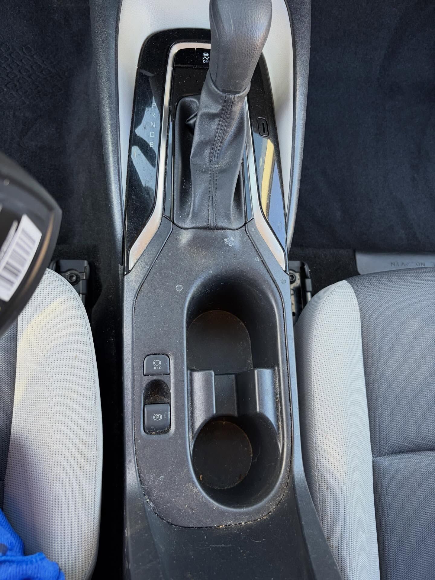 Car interior center console with manual gear shifter and cup holder between the front seats