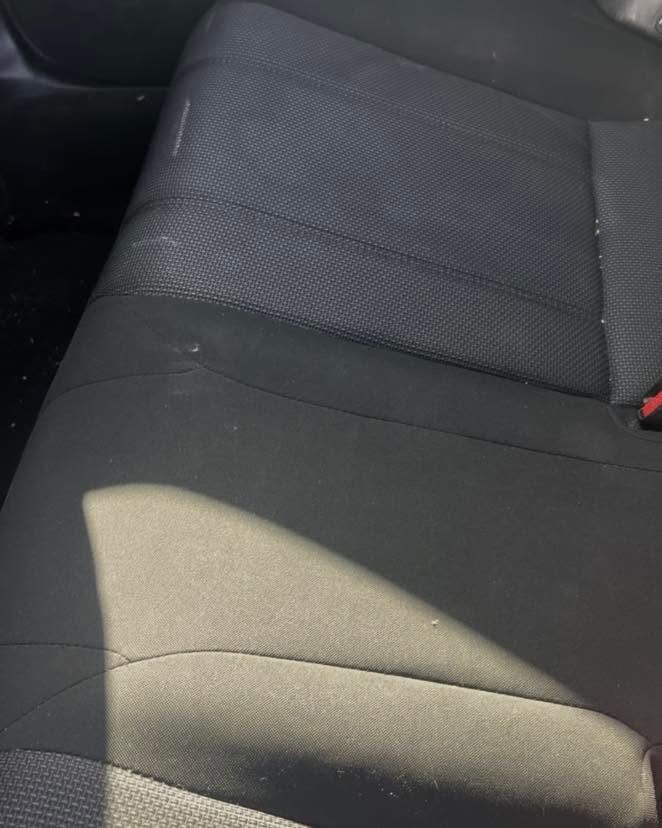 Close-up of a black and gray car seat with sunlight casting a bright shadow across it