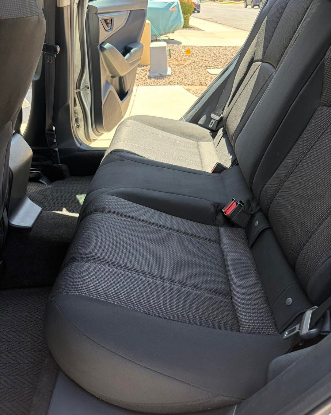 Car interior with front passenger door open and black cloth seats in sunlight
