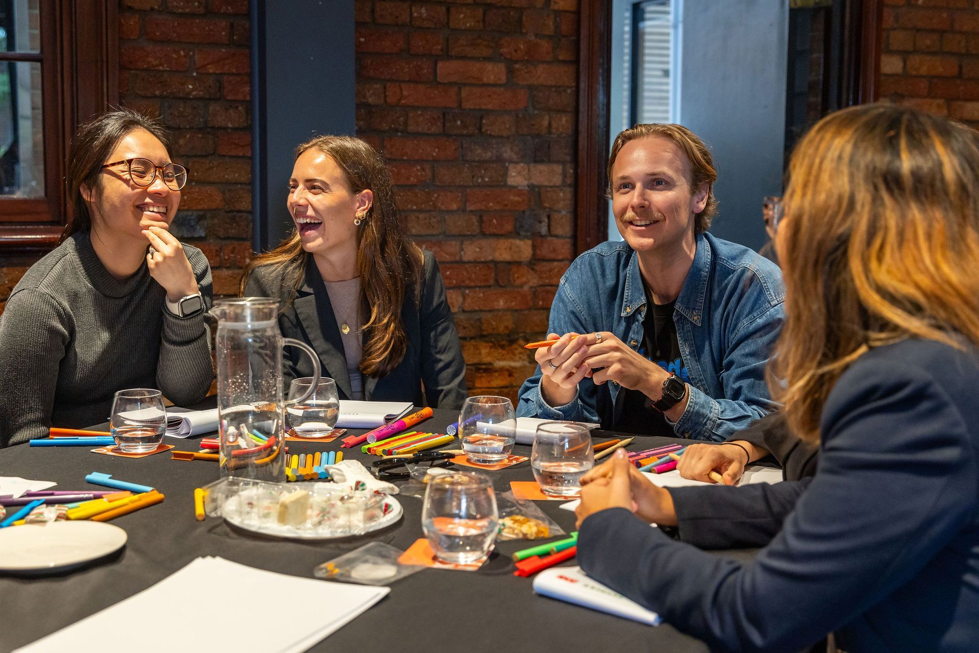 A group of people are sitting around a table laughing.