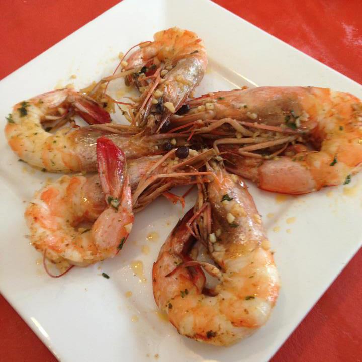 A white plate topped with shrimp on a red table cloth