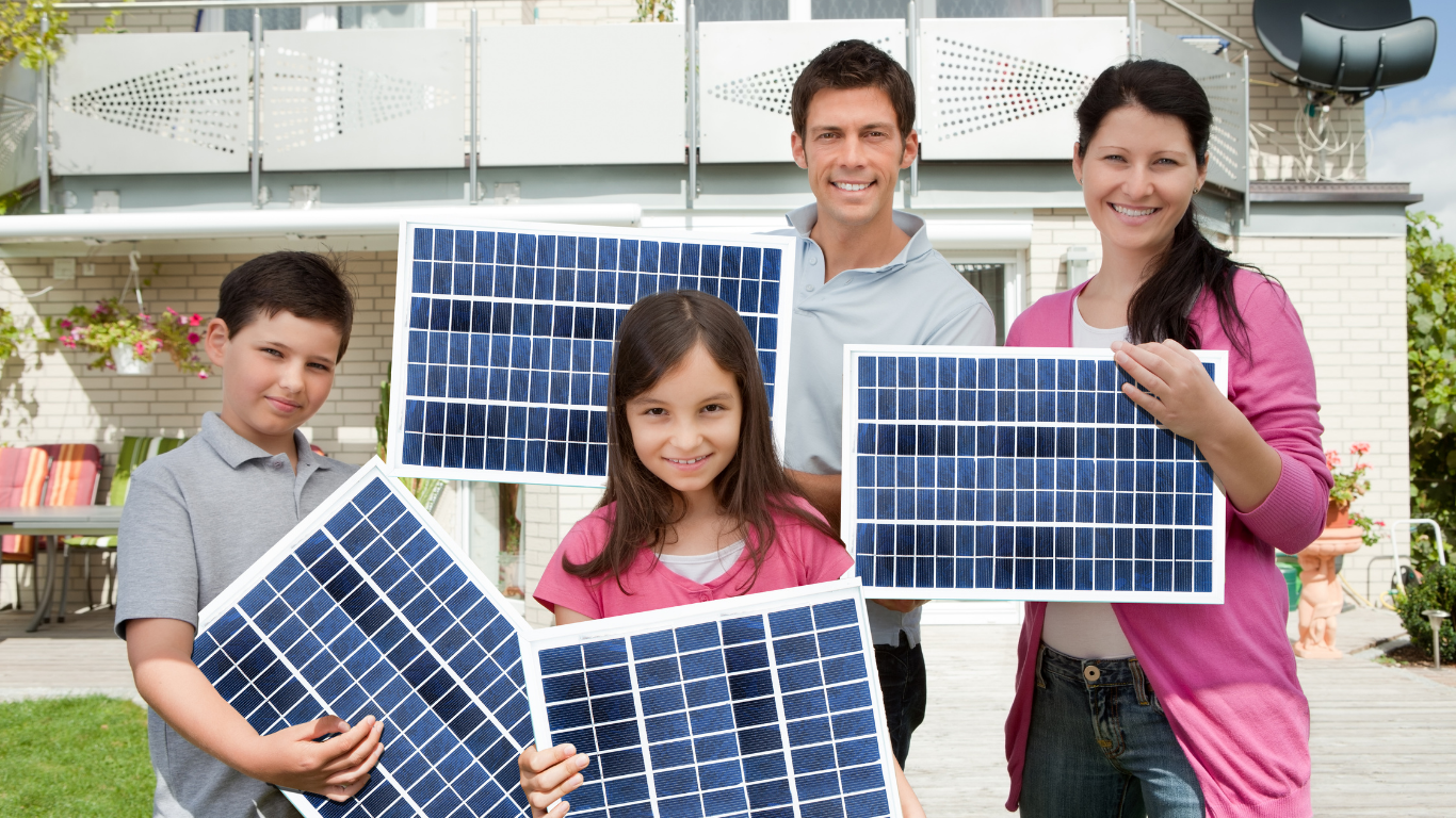 Family holding solar panels in front of a house, smiling outdoors