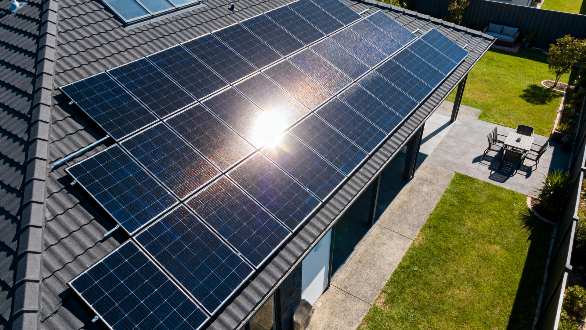 Solar panels installed on a residential roof. Sunlight glints off the dark panels.