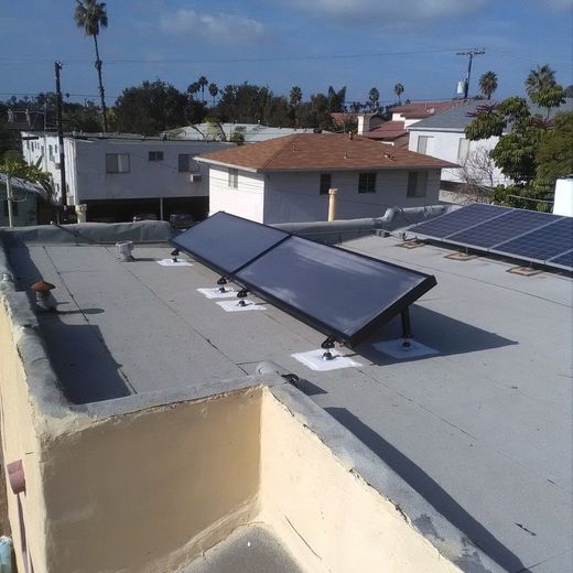 Solar panels on a flat rooftop against a clear, blue sky.