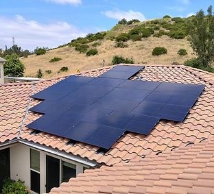 Solar panels installed on a terracotta tile roof with a hillside background.