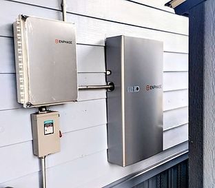 Enphase solar panel system installed on a blue-sided building with various electrical components.