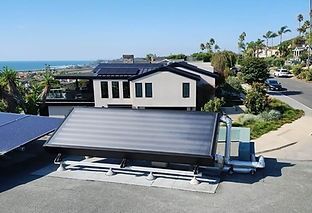 Solar thermal panels on a house roof overlooking the ocean and a street.
