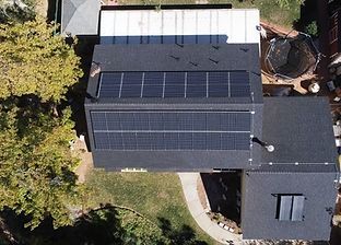 Aerial view of a house with solar panels on the roof and a trampoline in the yard.