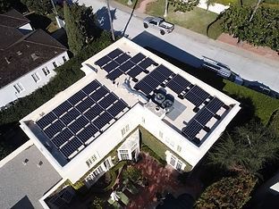 Solar panels on a large white roof of a house, with a truck parked on the street.