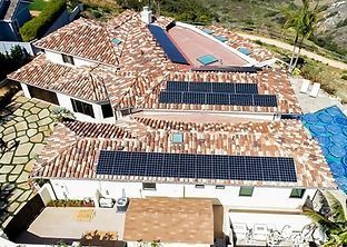 Residential home with a clay tile roof and solar panels. A pool is visible.