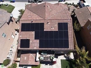 Overhead view of a house with solar panels installed on a terracotta-tiled roof.