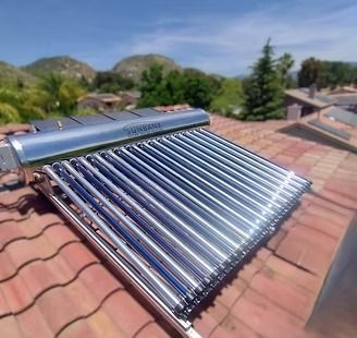 Solar panel installer working on rooftop under a clear blue sky. He wears a white helmet, orange jacket, and gloves.