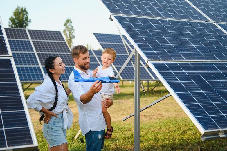 Solar panels on a building rooftop, absorbing sunlight. City in the background, sun setting.