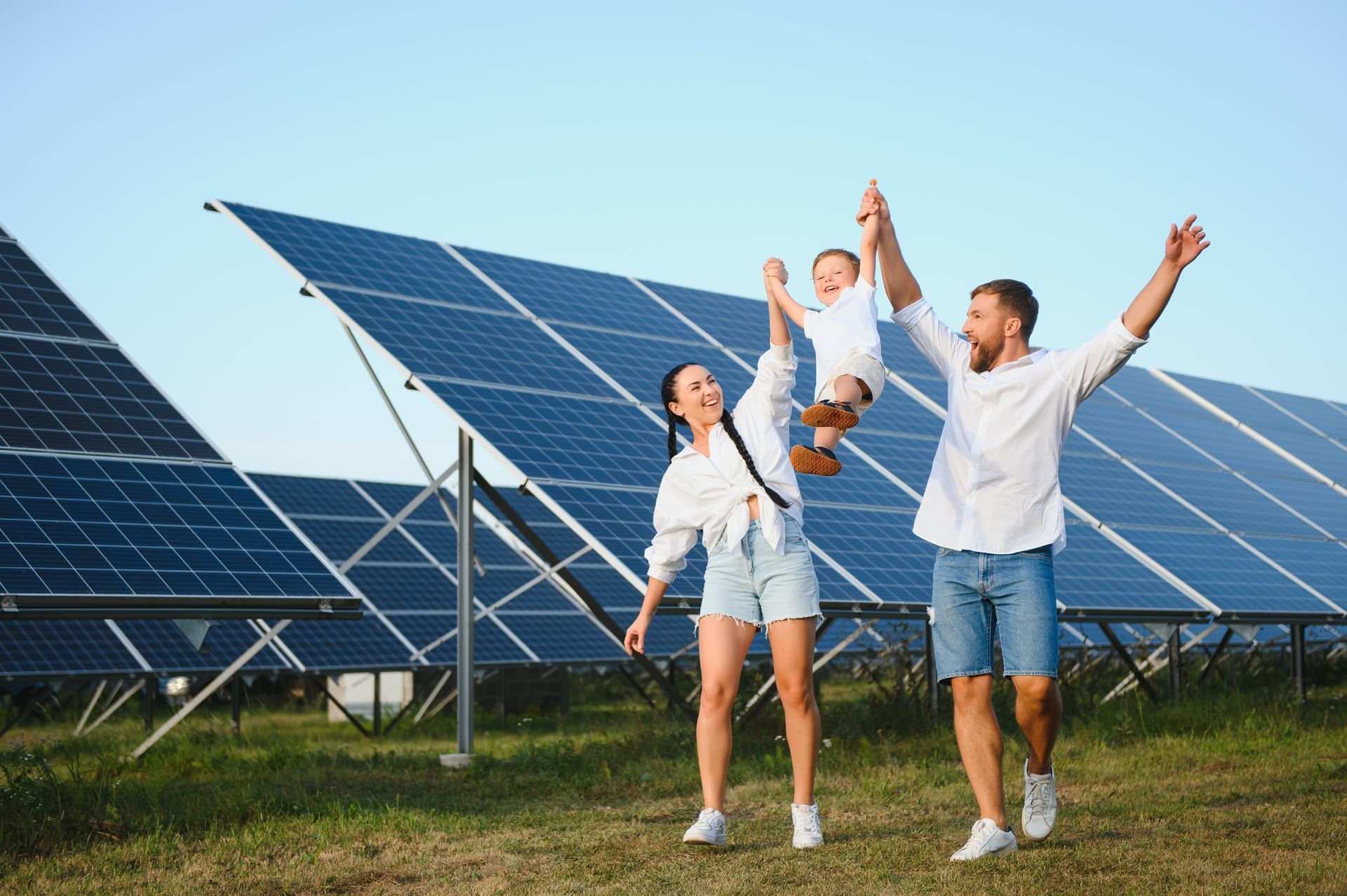 Three people celebrating in a solar panel field with arms raised