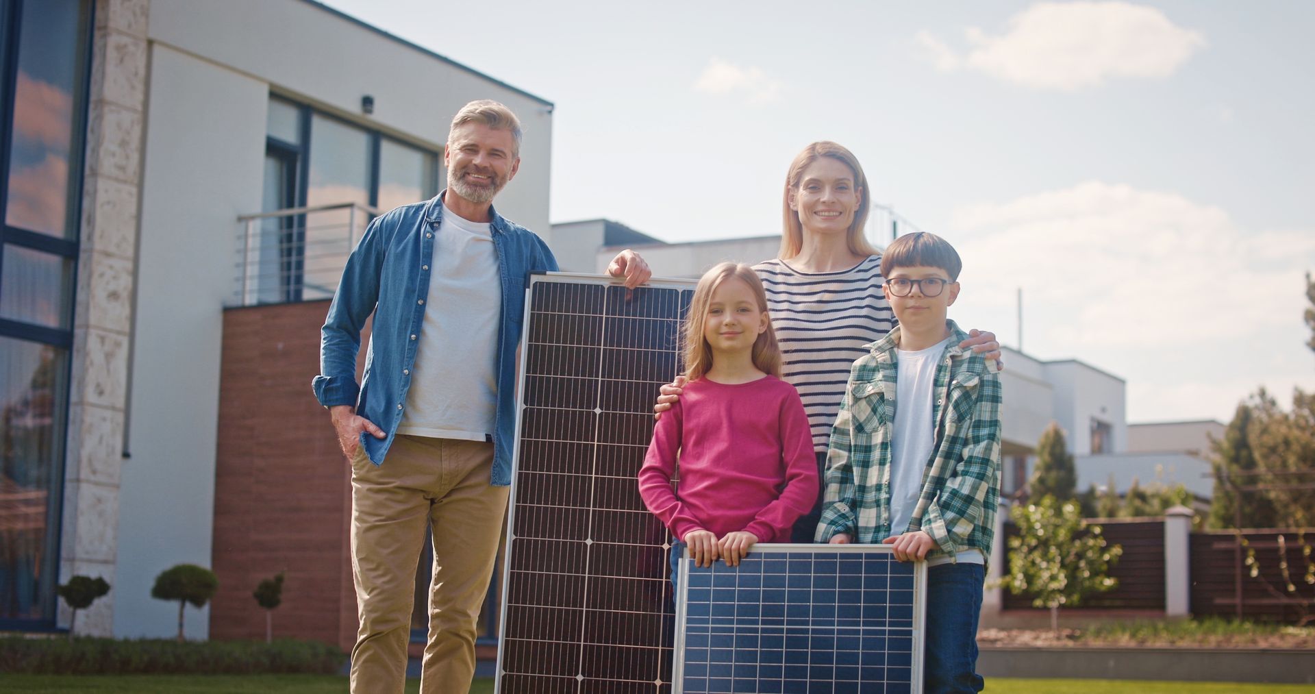Family standing outdoors with solar panels in front of a modern building, smiling in daylight