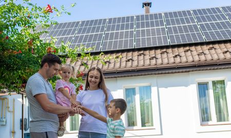 Solar panels on a roof, in front of a house, with ocean view.