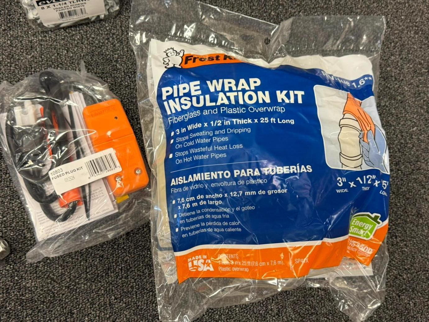 Two clear plastic packages on a gray surface: one with a pipe wrap insulation kit,