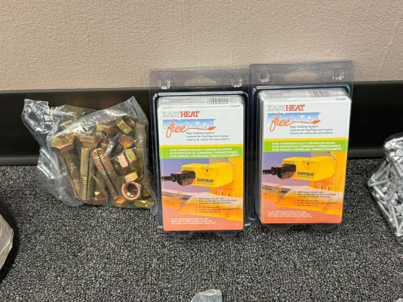Hardware supplies: bolts in a bag, two boxes of Freeze-Heat, on a textured surface.