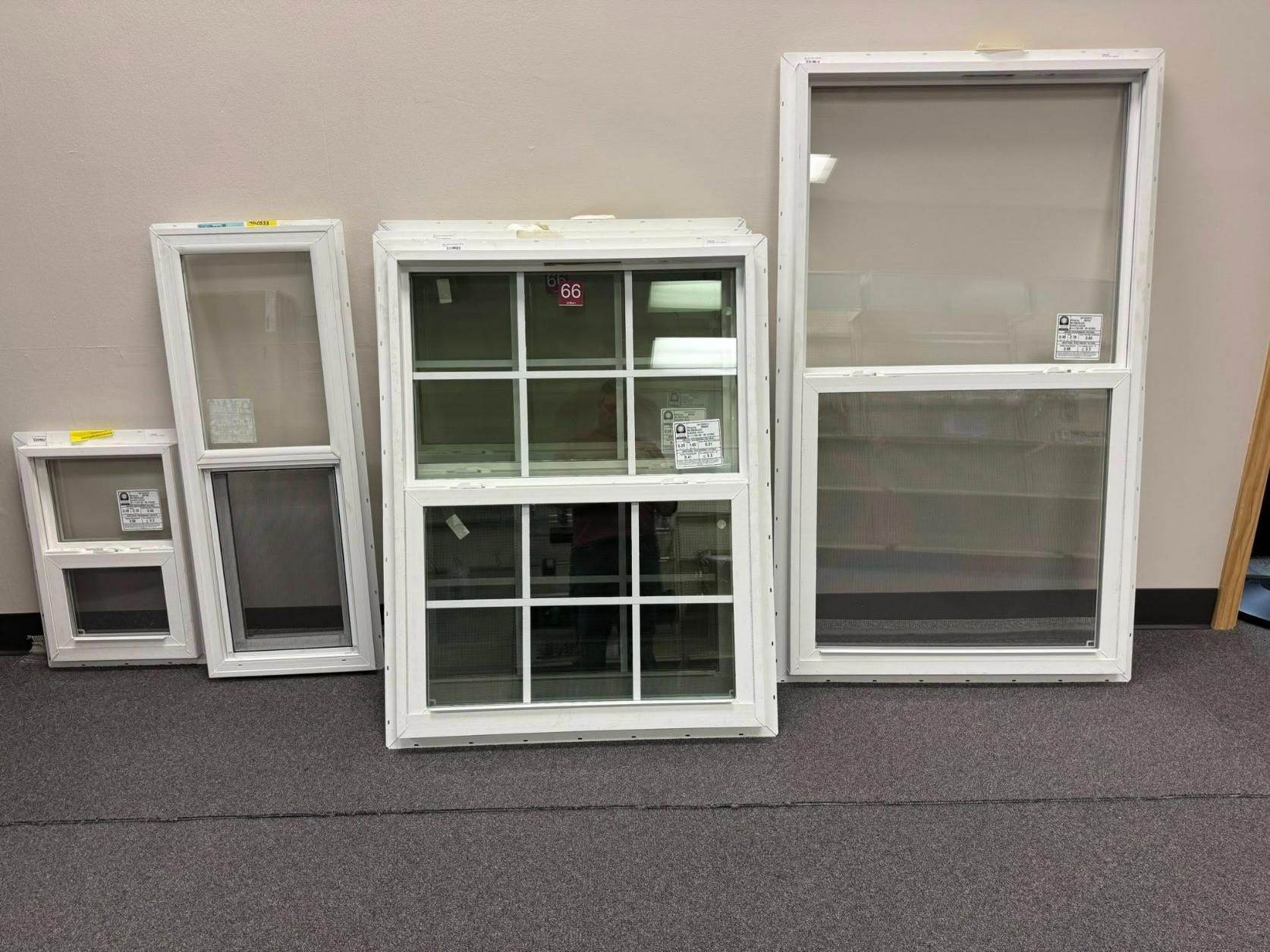 Five white-framed windows of varying sizes displayed against a neutral wall and carpeted floor.