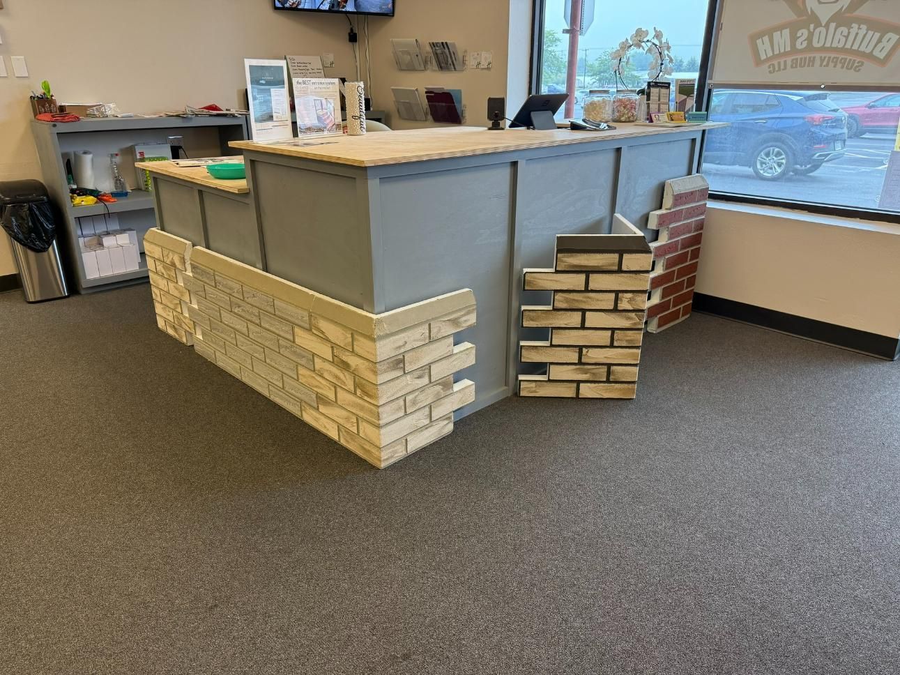 A retail counter with brick veneer samples. The counter is gray, with wood top and displays brick samples.