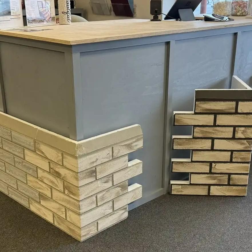 Close-up of a counter with brick-like paneling. Grey counter and panels, beige brick pattern.