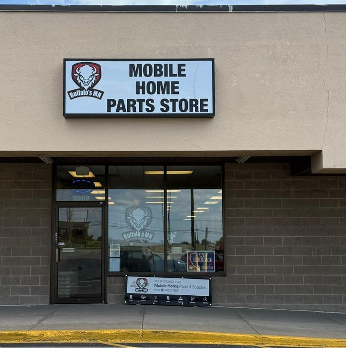 Exterior of a mobile home parts store with a skull logo on a tan building.