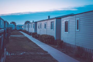 Row of white beach houses with a sidewalk, under a blue twilight sky.