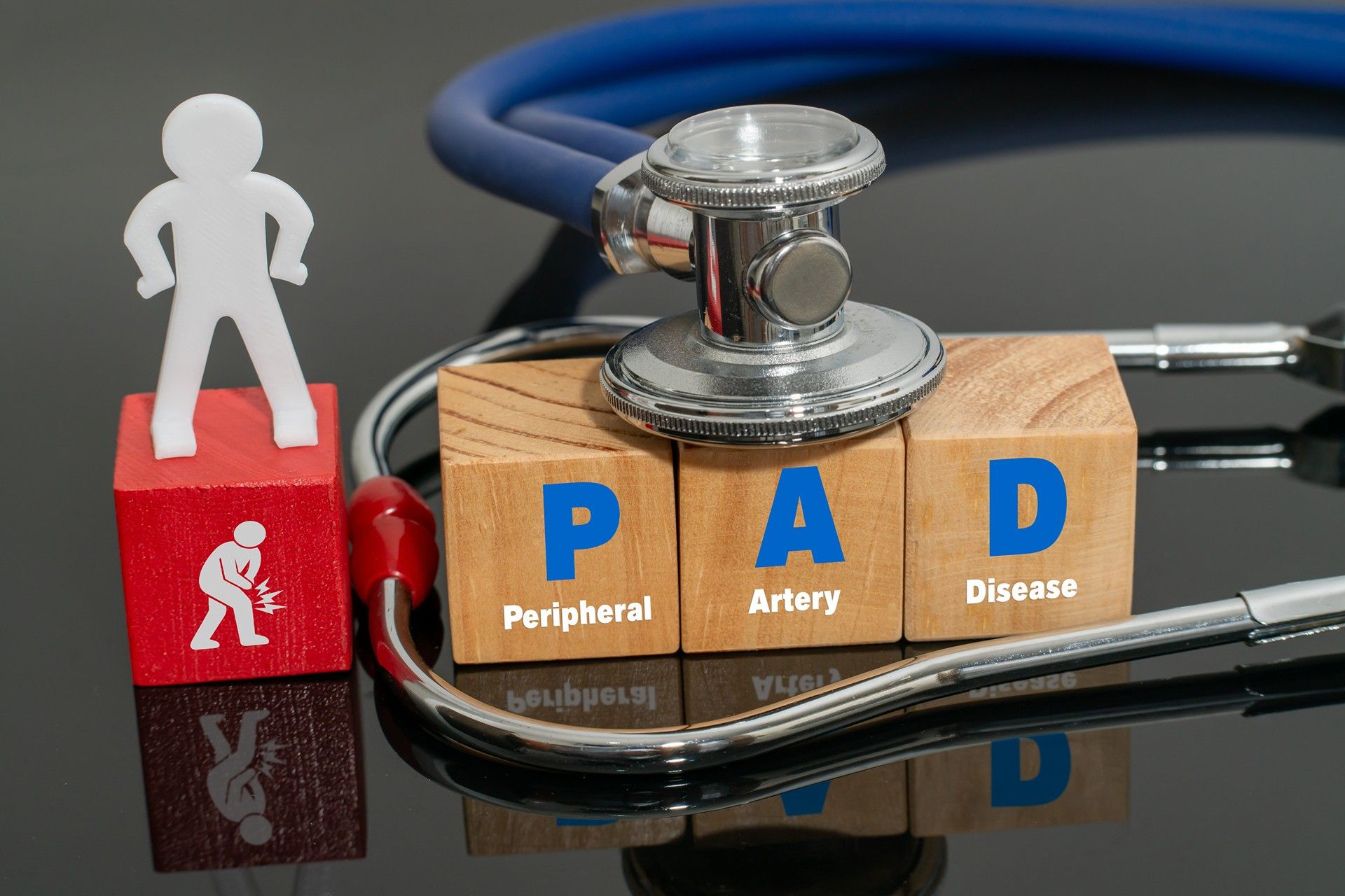 Stethoscope on PAD wooden blocks with a small figure, symbolizing peripheral artery disease screening
