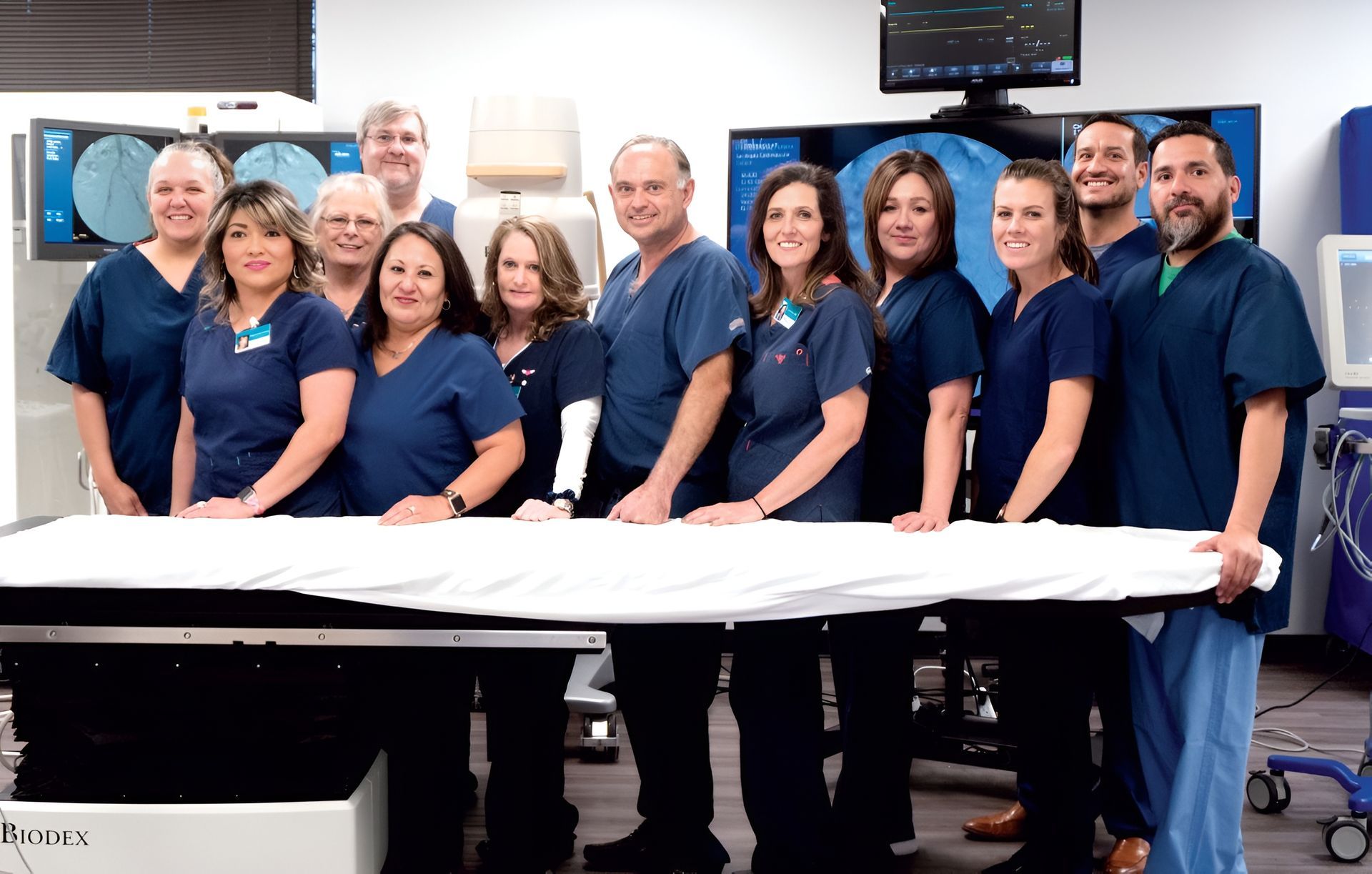 Group of staff in navy uniforms standing behind a large white print in an office or lab setting