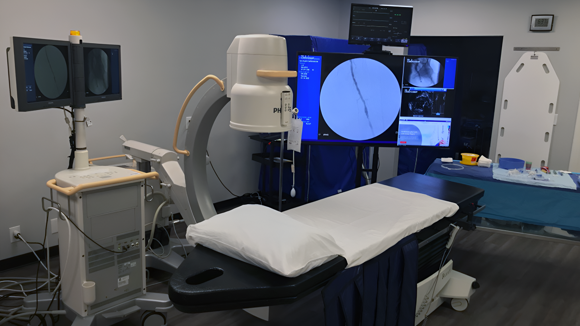 Medical imaging room with a CT scanner, patient table, and monitors displaying scans