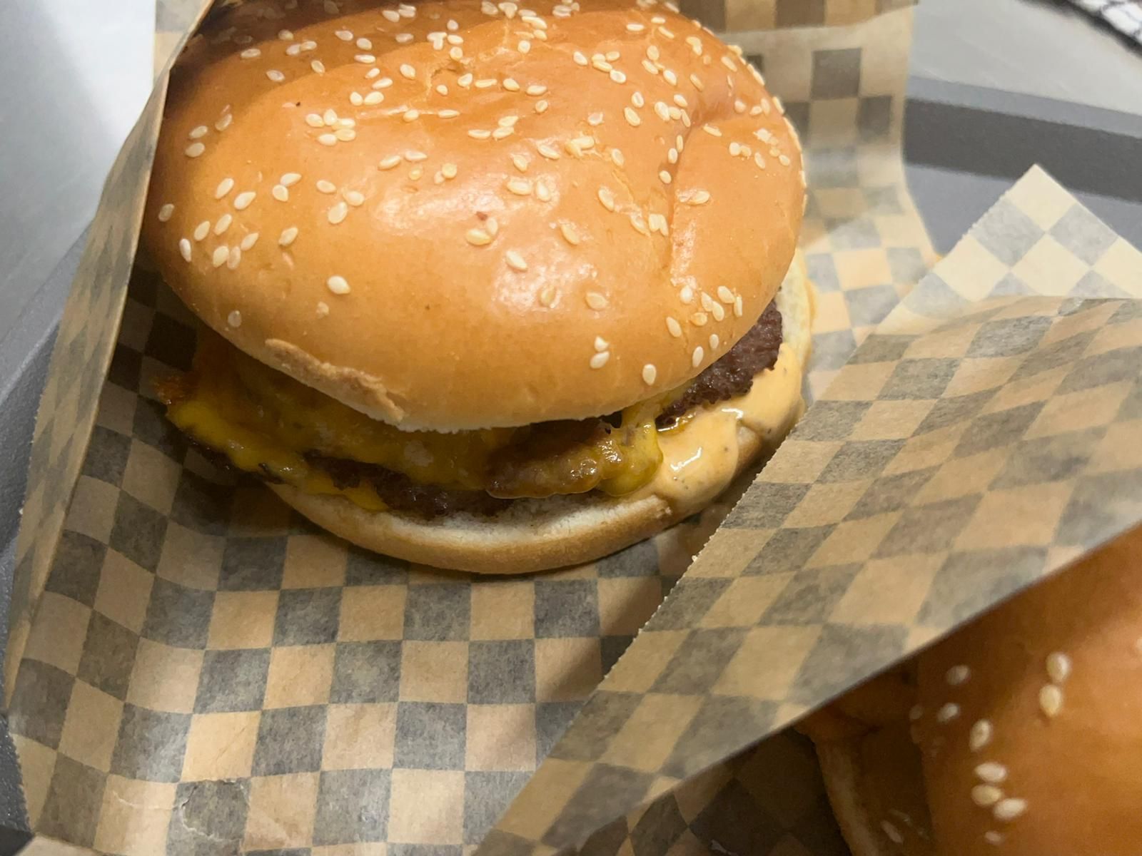 Cheeseburger ai semi di sesamo in un involucro a scacchi su un tavolo