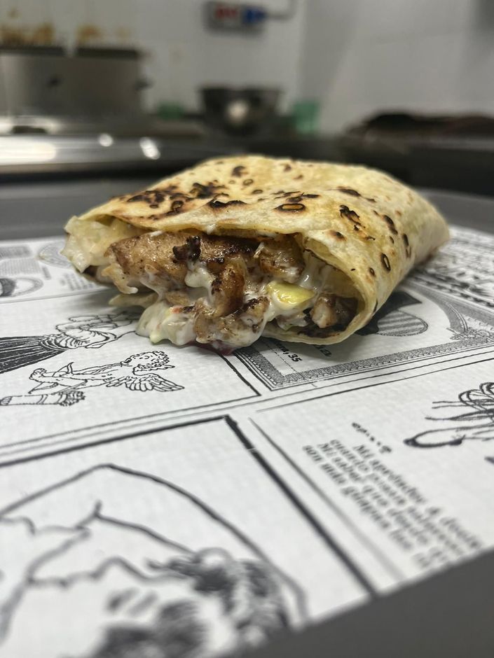 Tortilla grigliata piegata con ripieno fuso su carta stampata, sul bancone della cucina.
