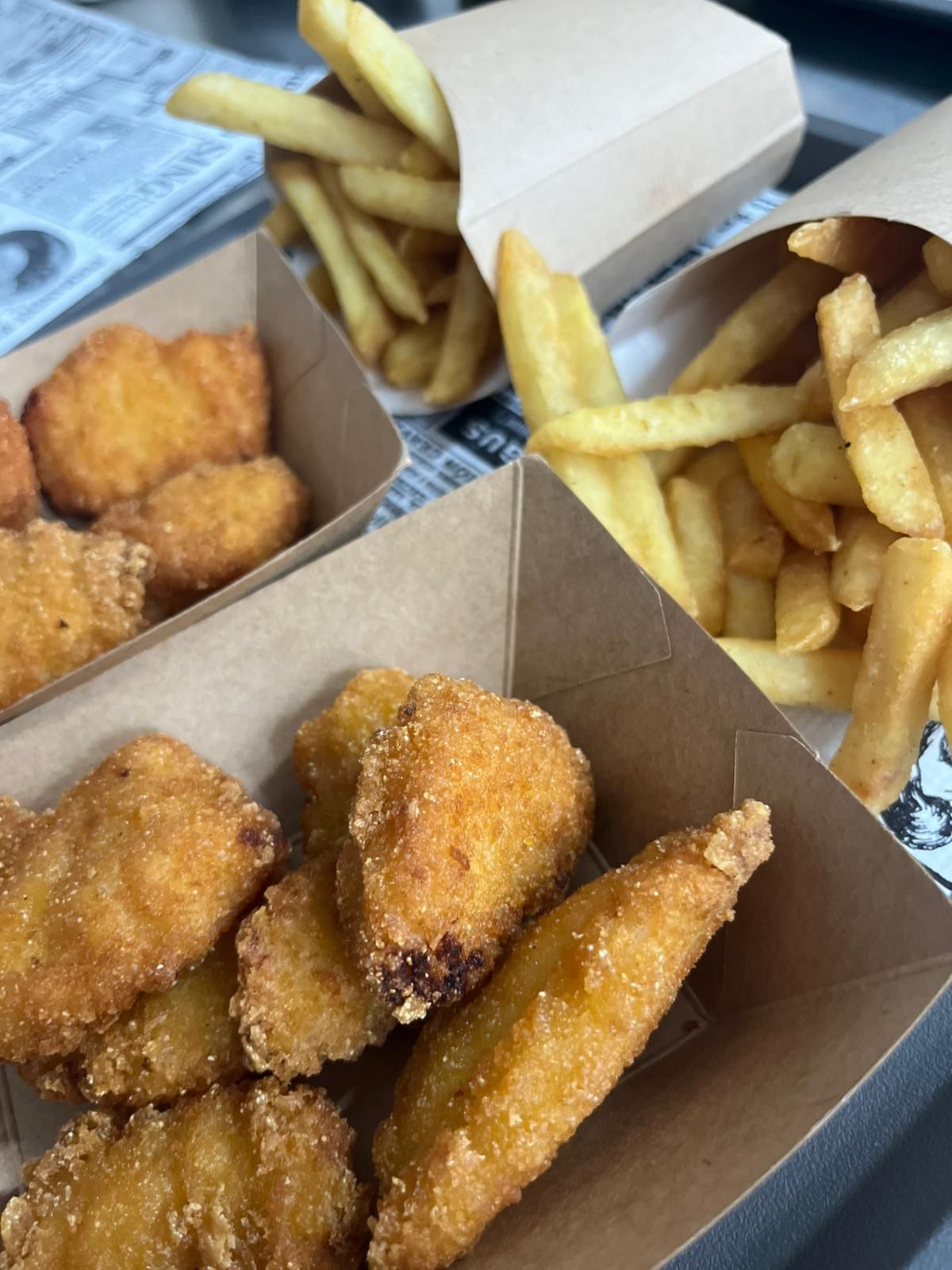 Scatole da asporto di crocchette di pollo fritte e patatine fritte su un tavolo