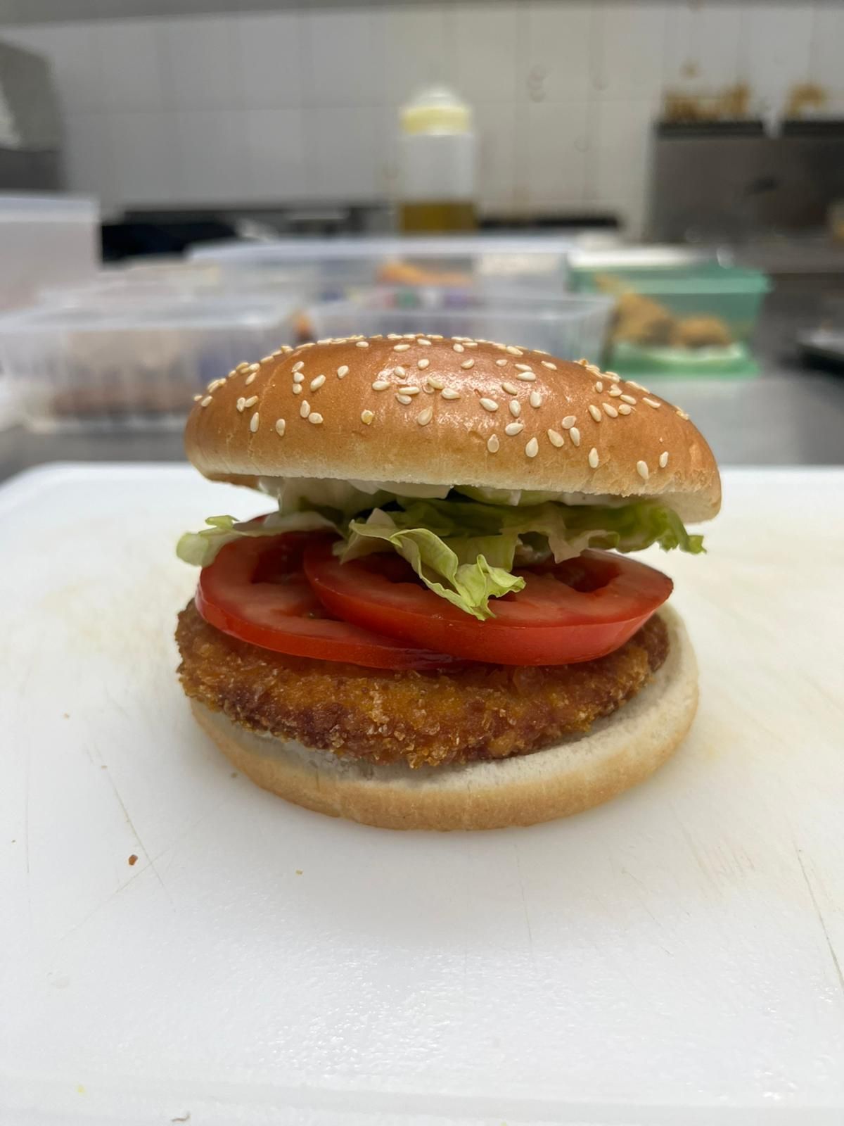 Panino vegetariano con lattuga e pomodoro su un panino al sesamo in una zona di preparazione della cucina