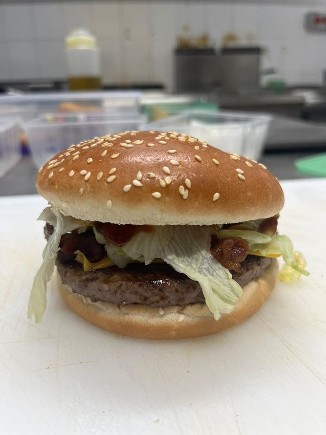 Hamburger con semi di sesamo e lattuga su un tagliere bianco in cucina
